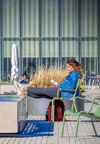 A woman props her feet up on one of the fountains at Tisch Park on the Danforth Campus to enjoy a good book.