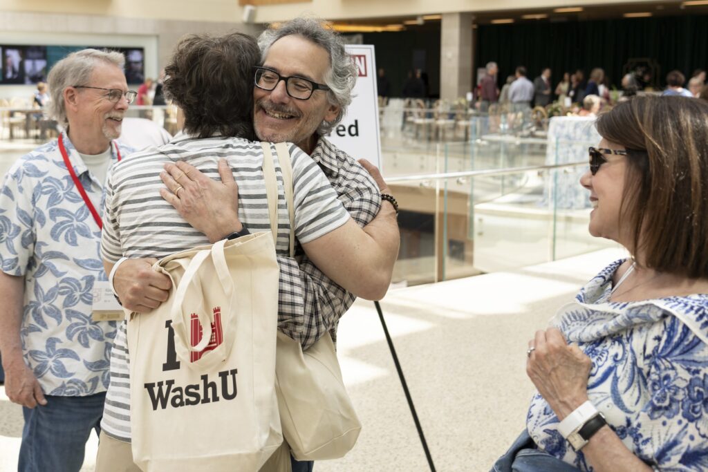 alums hug at dinner event