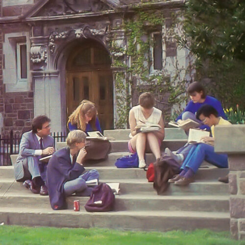 Color photo of students and a professor sitting on steps on the WashU campus