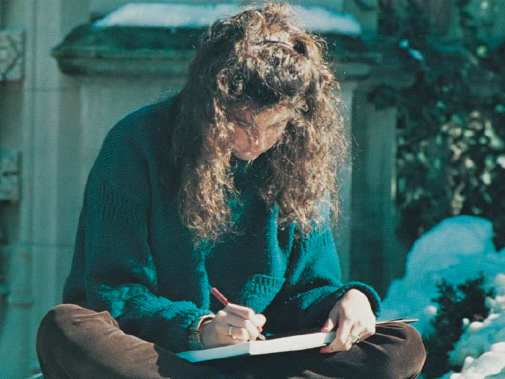 Color photo of WashU student in the 1980s studying on a snow-covered campus