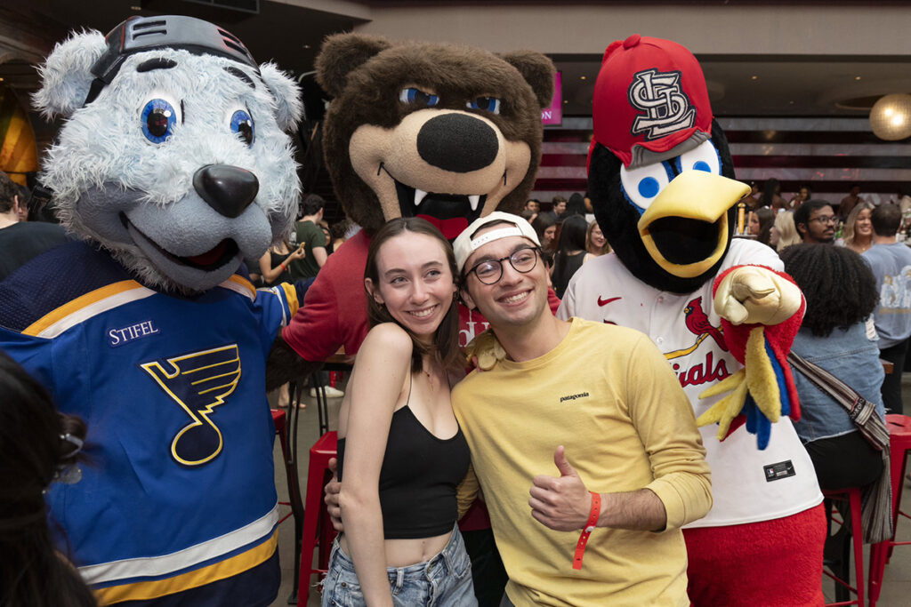 Two 2024 graduates pose for a photo with local mascots during the 2024 graduation party