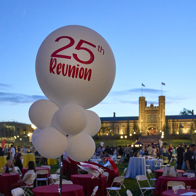 A view of the set-up for a reunion event, with white balloons with '25th Reunion' printed on them