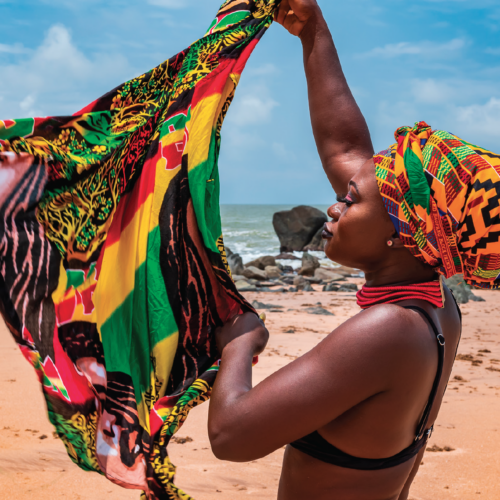 African woman on beach holding scarf