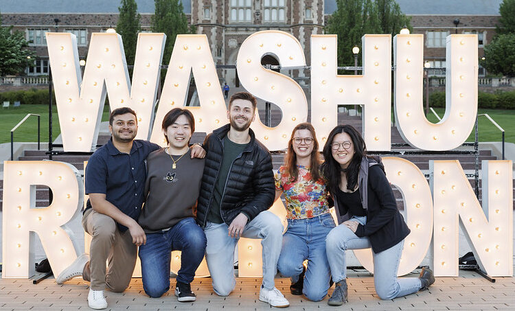 alums pose for photo in front of WashU reunion sign